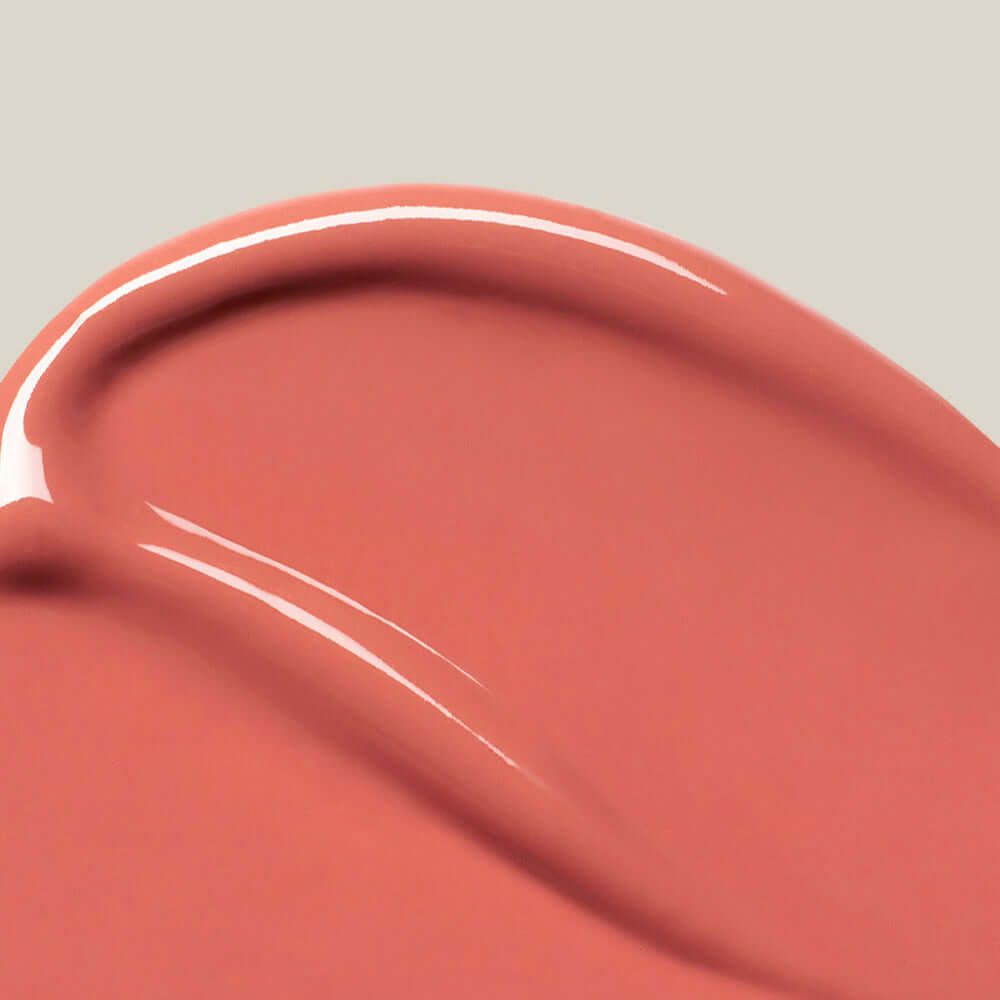 Close-up of SU:M37 Skin-Stay Glossy Lip Balm texture in peachy pink color, showcasing the smooth and glossy finish.