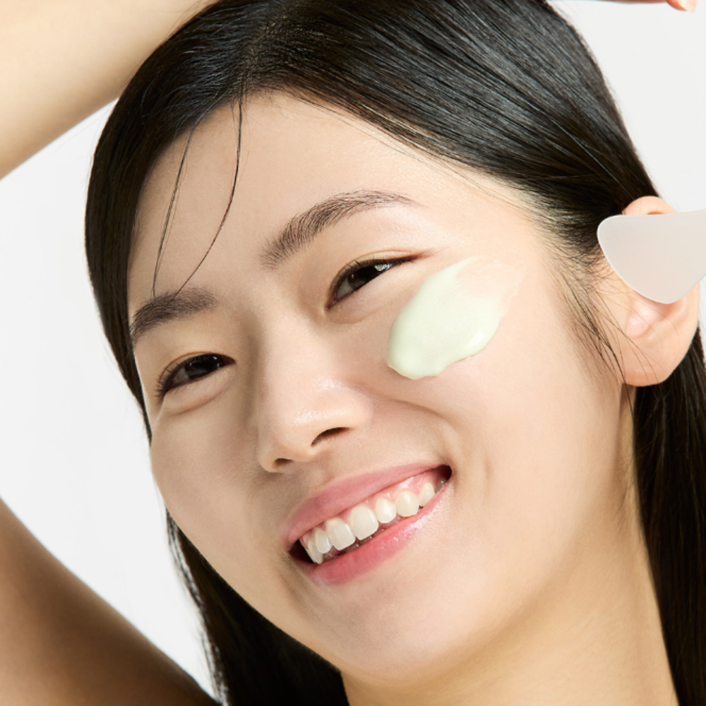 Woman applying SUNGBOON EDITOR Boosting Modeling Pack Green Tomato Pore Tightening to her face for skincare.