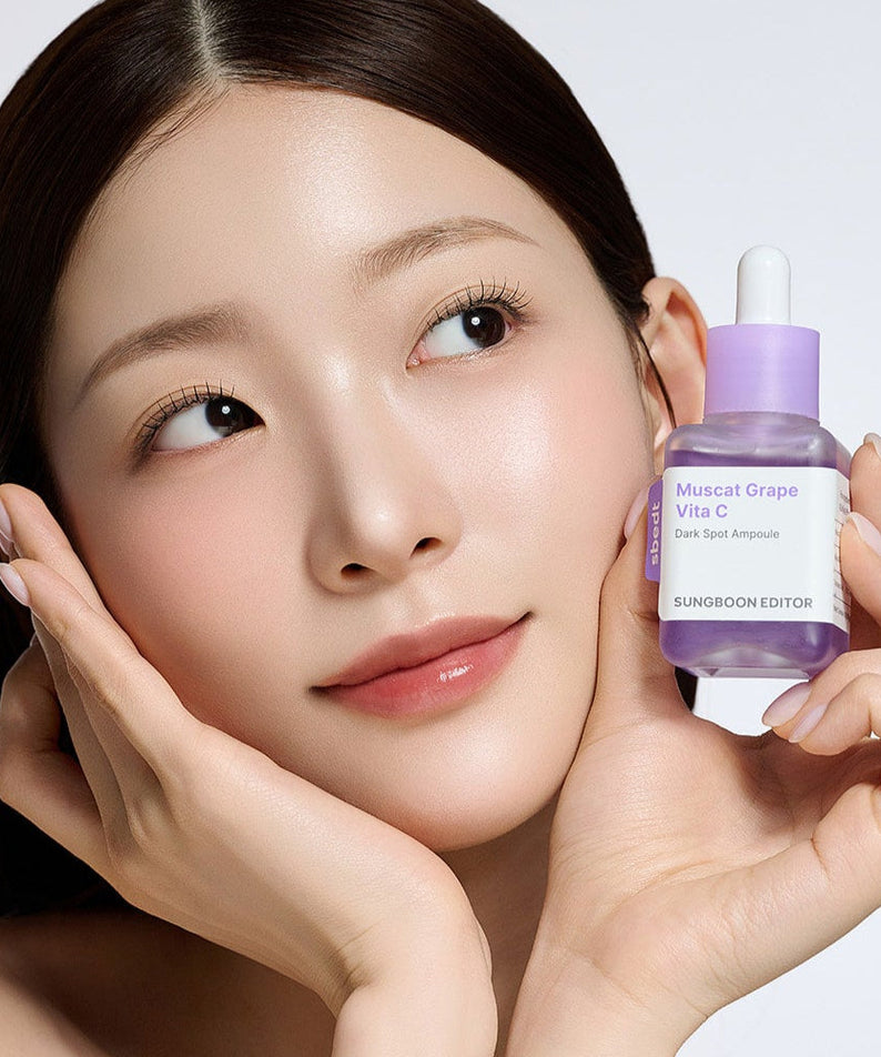Woman holding SUNGBOON EDITOR Grape Vita C Dark Spot Whitening Ampoule 40ml skincare product close to her face.