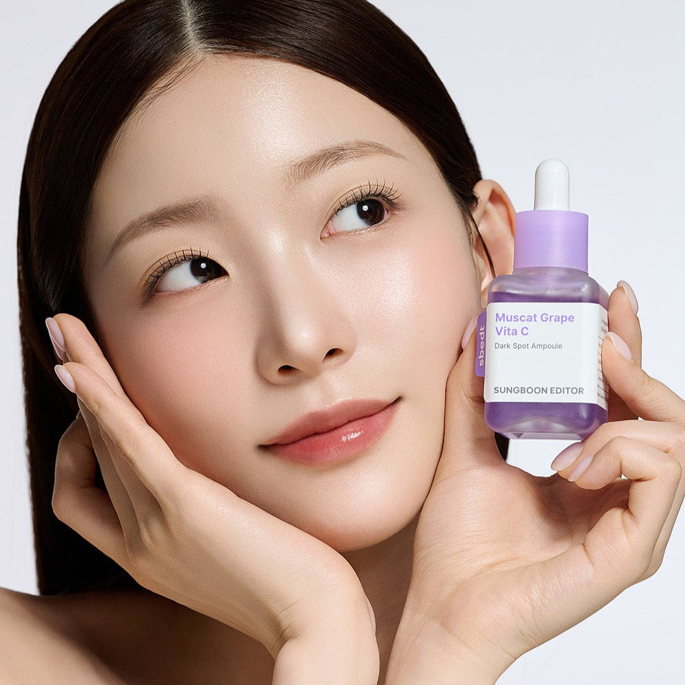 Woman holding SUNGBOON EDITOR Grape Vita C Dark Spot Whitening Ampoule 40ml skincare product close to her face.