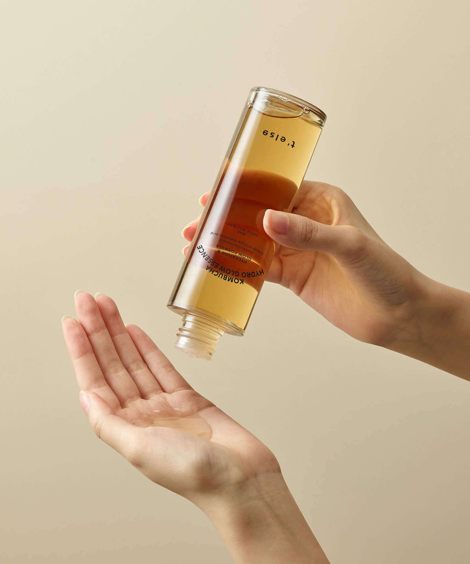 Hands using T'ELSE Kombucha Hydro Glow Essence 150ml for skincare routine