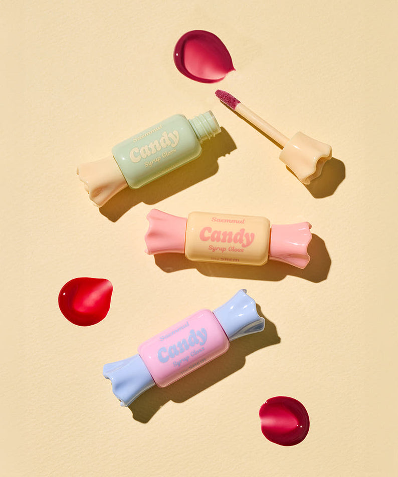 THE SAEM Saemmul Candy Syrup Gloss packaging with open gloss tube and colorful candy-shaped containers on beige background.