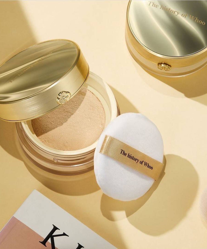 THE WHOO Gong Jin Hyang Mi Luxury Luminous Powder with puff on table, elegant packaging in gold with branding details.