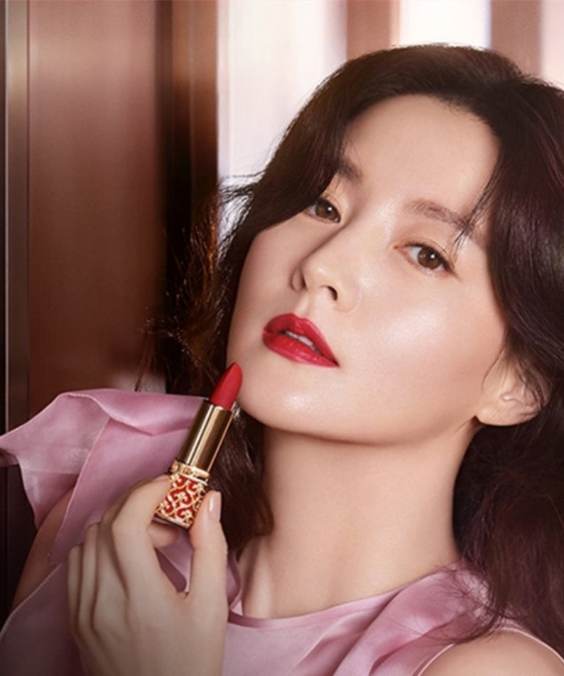 Model applying THE WHOO Gong Jin Hyang Mi Velvet Lip Rouge, showcasing vibrant lipstick color and luxurious packaging.