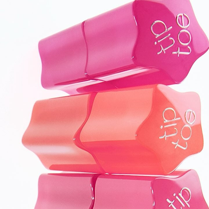 Stack of TIP TOE Glowit Sorbet Tint tubes in vibrant pink and peach shades for lip and cheek tinting