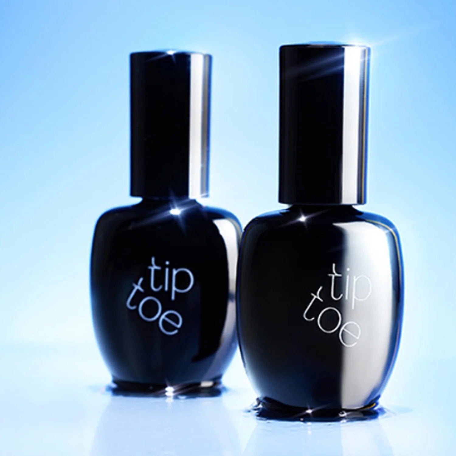 Two bottles of TIP TOE Sheer Topcoat Nail Polish on a reflective surface.
