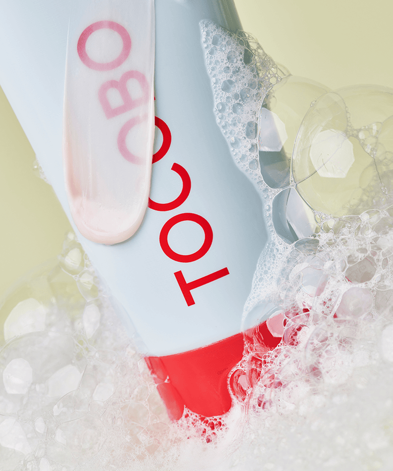 TOCOBO Coconut Clay Cleansing Foam tube surrounded by foamy bubbles, emphasizing its cleansing properties.
