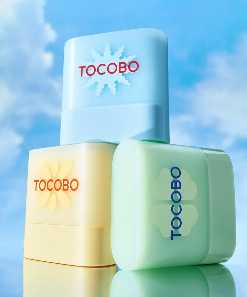 TOCOBO Mini Sun Stick Trio featuring three sunscreen sticks against a blue sky background, perfect for on-the-go sun protection.
