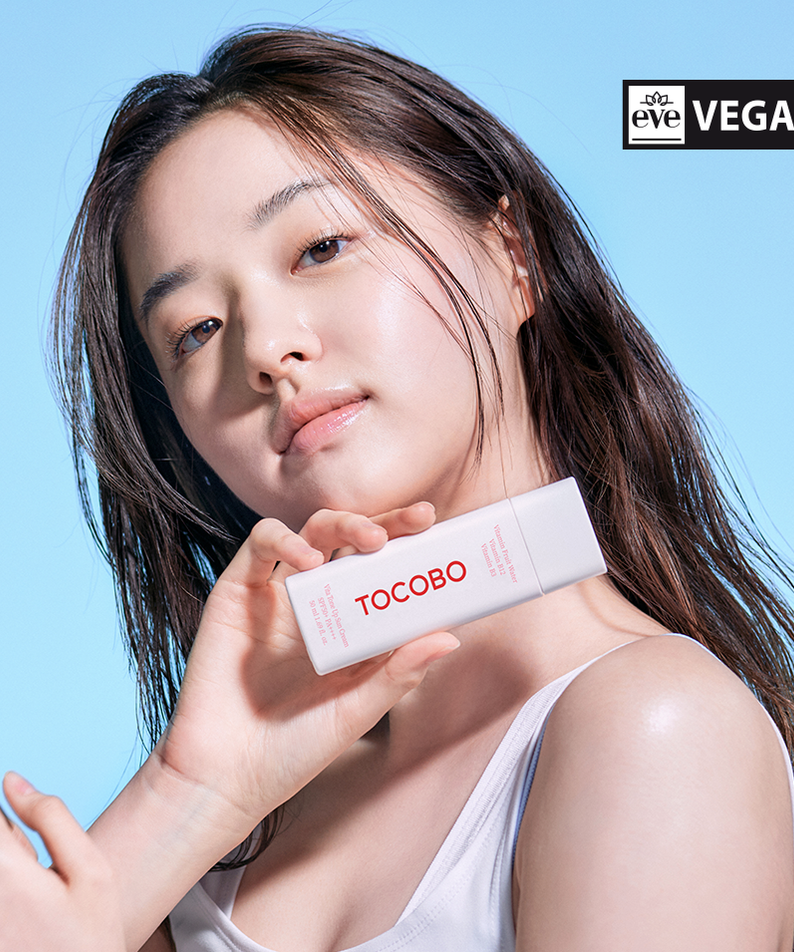 TOCOBO Vita Tone Up Sun Cream 50ml held by a person with a blue background and vegan certification badge.