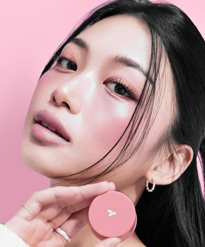 Woman holding TONY MOLY Cheek Tone Lip & Cheek Duo Balm against pink background