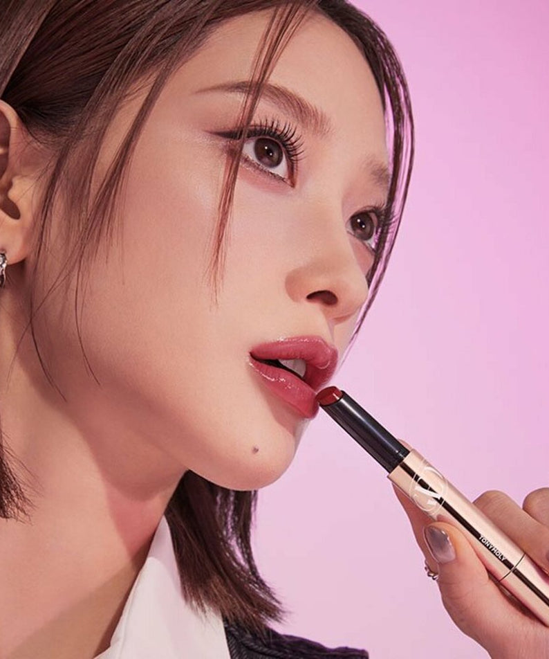 Woman applying TONY MOLY Get It Tint Glaze Balm on lips against pink background
