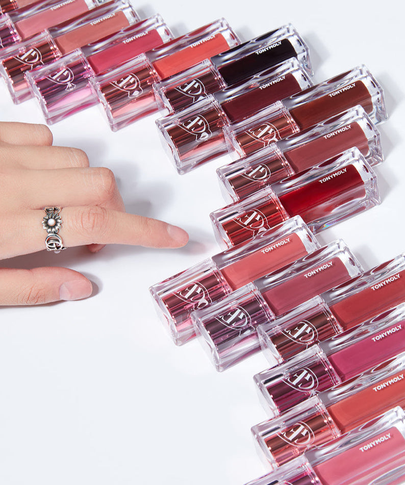 Hand reaching for TONY MOLY Get It Tint Waterful Butter lip colors arranged in a row