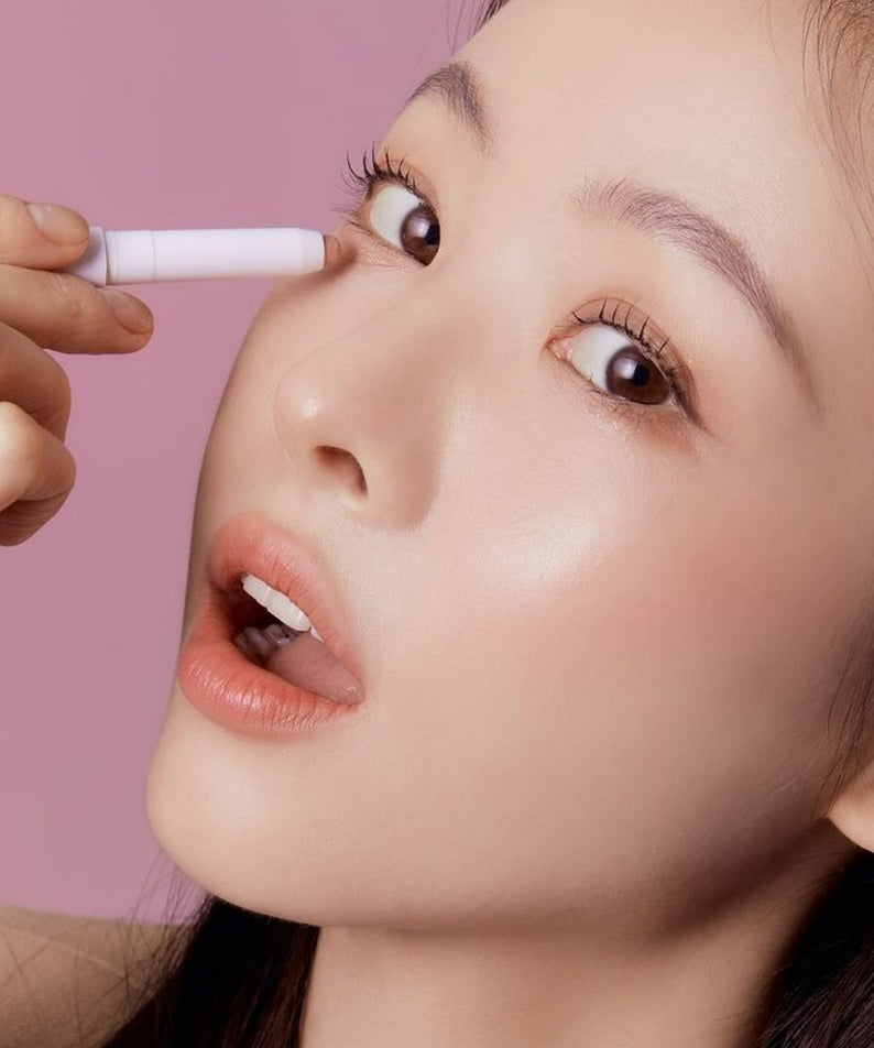 Woman applying TONY MOLY The Shocking Color Fixing Stick Shadow to eyelid with pink background.