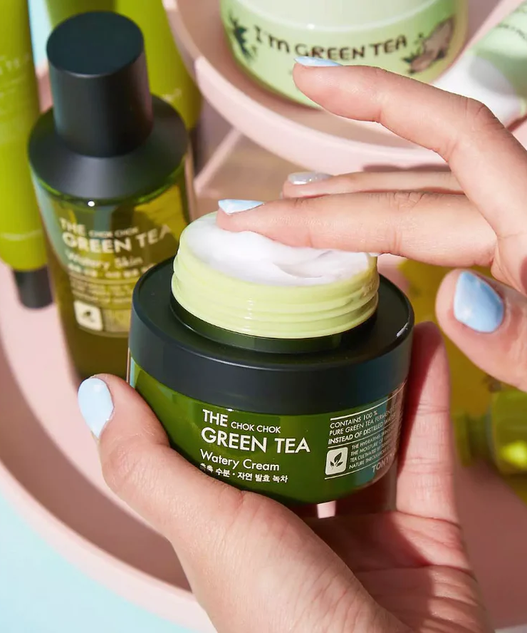 Person applying TONYMOLY More Moist Green Tea Gel Cream 60ml with skincare products in background.