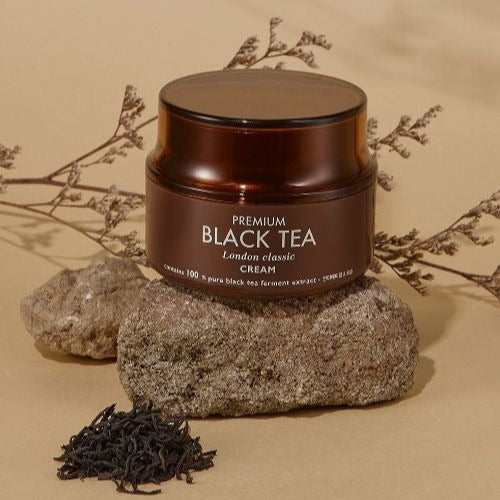 TONYMOLY Premium Blacck TeaLondon Classic Cream 50ml jar on natural stone with tea leaves and twigs background