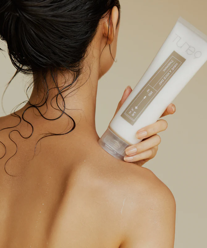 Person holding TONYMOLY Tune 9 Have A Nice Day Treatment 250ml with wet hair.