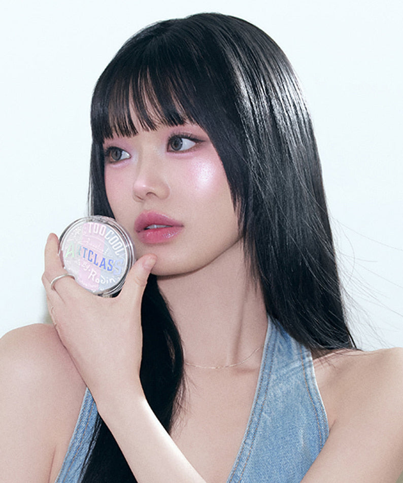 Model holding TOO COOL FOR SCHOOL Art Class By Rodin Highlighter with radiant makeup look