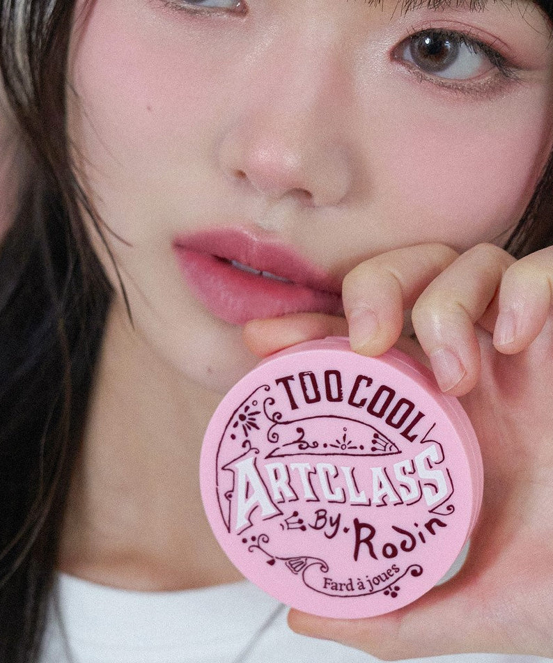 Person holding TOO COOL FOR SCHOOL By Rodin Blusher in pink packaging, showcasing product design and color.