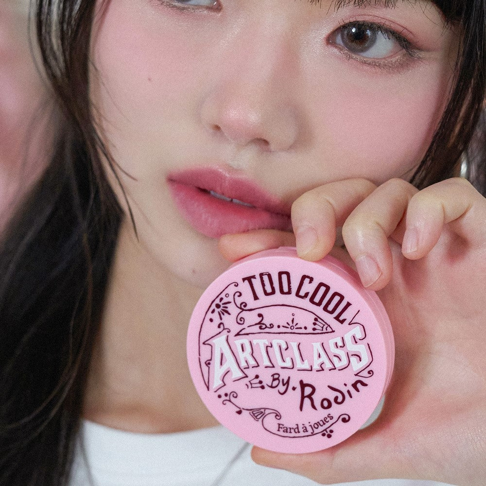 Person holding TOO COOL FOR SCHOOL By Rodin Blusher in pink packaging, showcasing product design and color.
