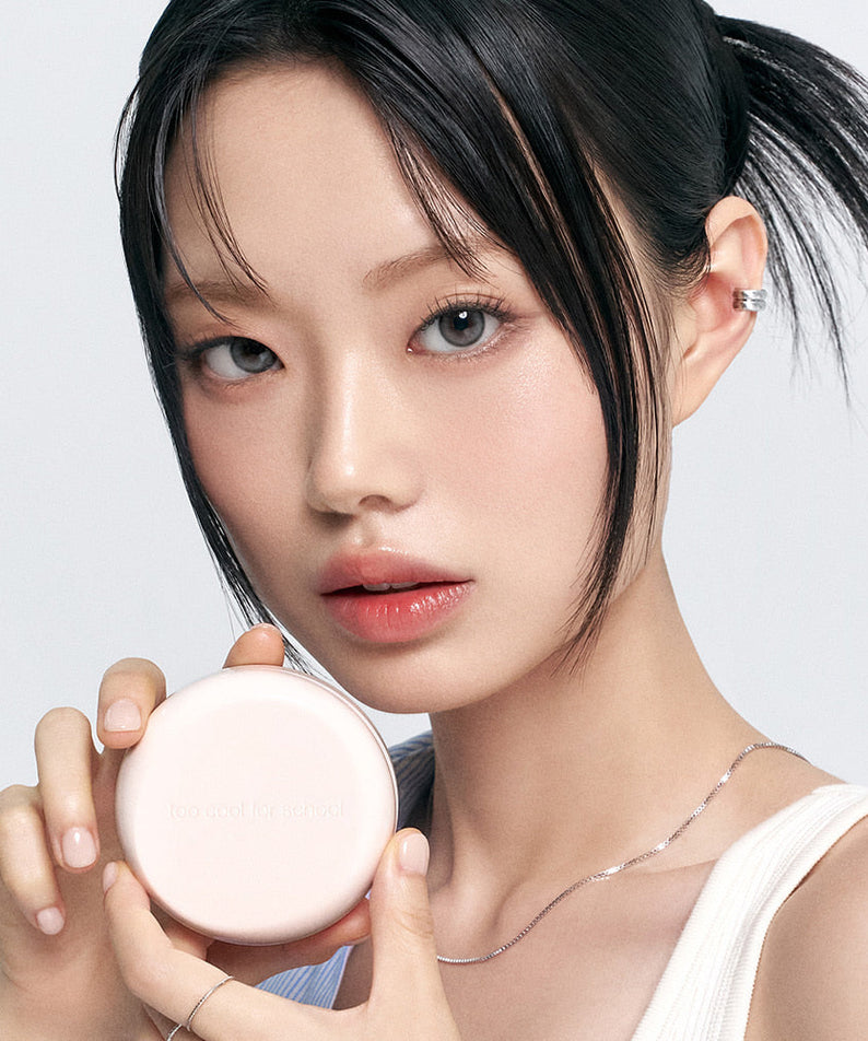 Model holding TOO COOL FOR SCHOOL Fixing Dew Cushion [Main Product + Refill], showcasing beauty product packaging.
