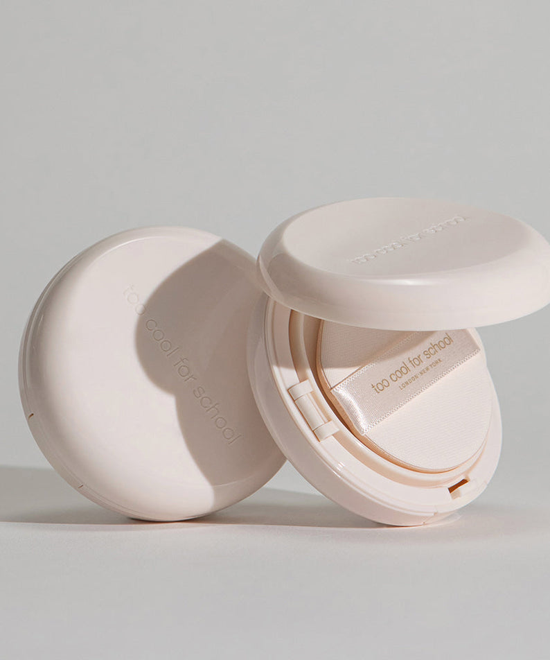 TOO COOL FOR SCHOOL Fixing Dew Cushion [Main Product + Refill] compact open with neutral beige packaging on grey background.