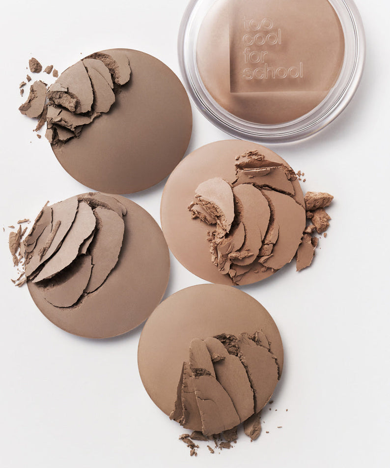 TOO COOL FOR SCHOOL Veiled Contour pressed powder makeup collection with four shades and open compact on white background.