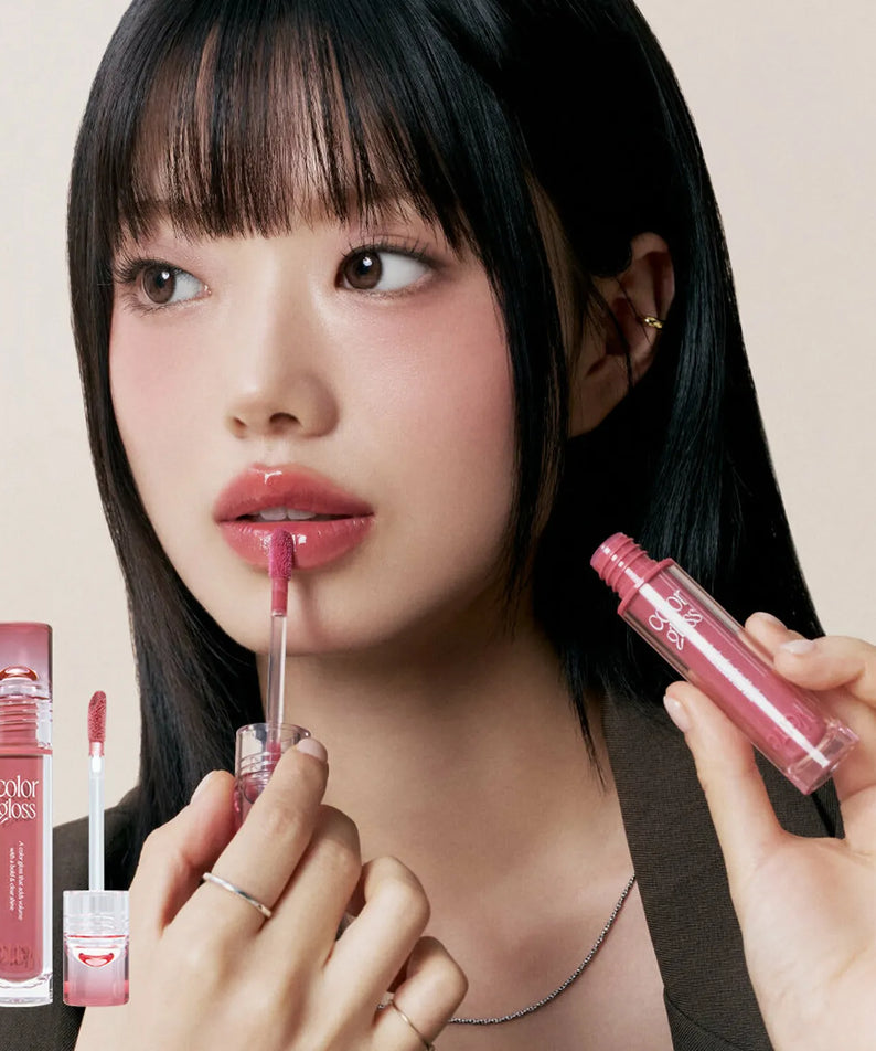 Woman applying TOO COOL FOR SCHOOL Verre Color Gloss lipstick, showcasing sleek and glossy lip finish.