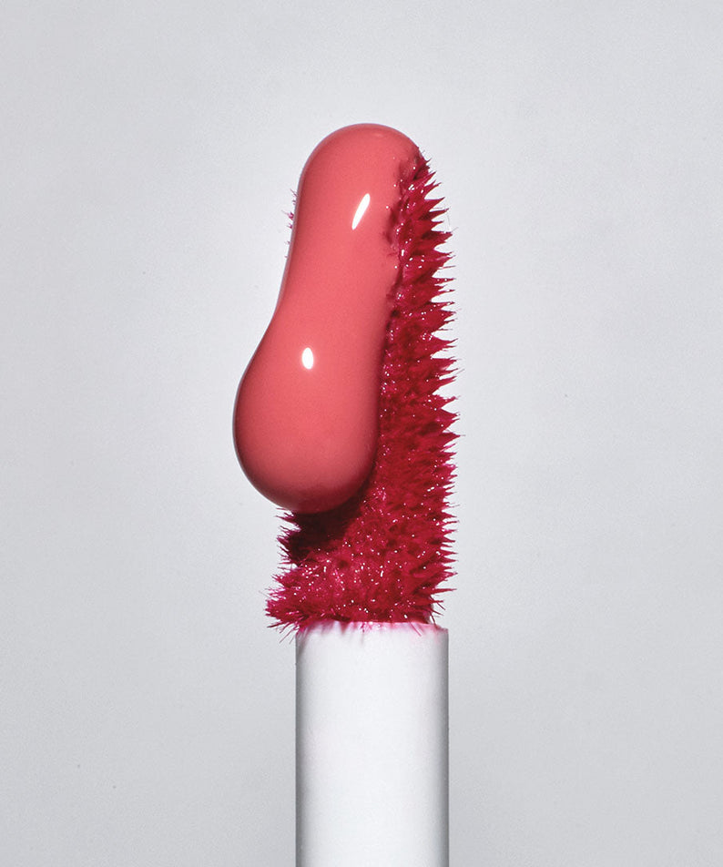 Close-up of TOOQ Gentle Kiss Glow Tint applicator with vibrant pink tint on brush.
