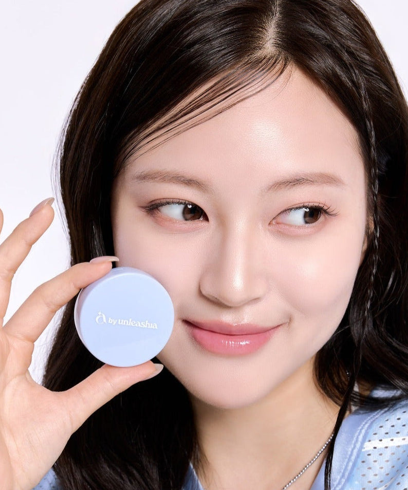 Woman holding UNLEASHIA Be Be Blue Cushion, showing vibrant packaging and radiant skin.
