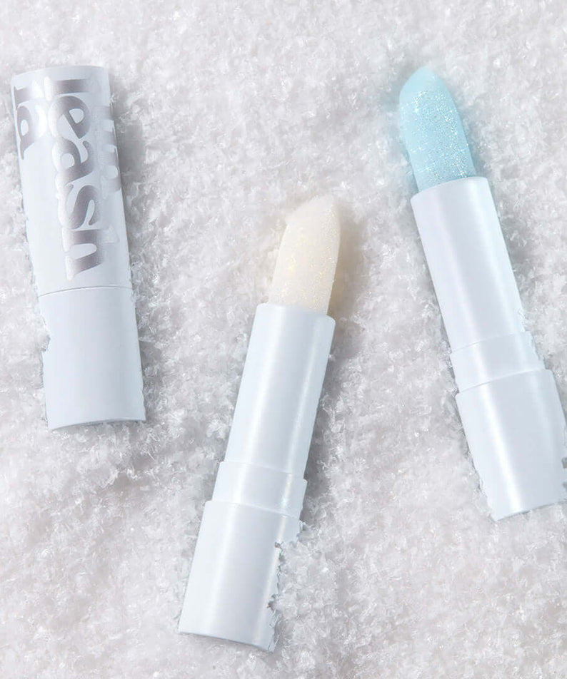 UNLEASHIA Glacier Vegan Lip Balm in snowy background showcasing two open lip balms with icy colors.