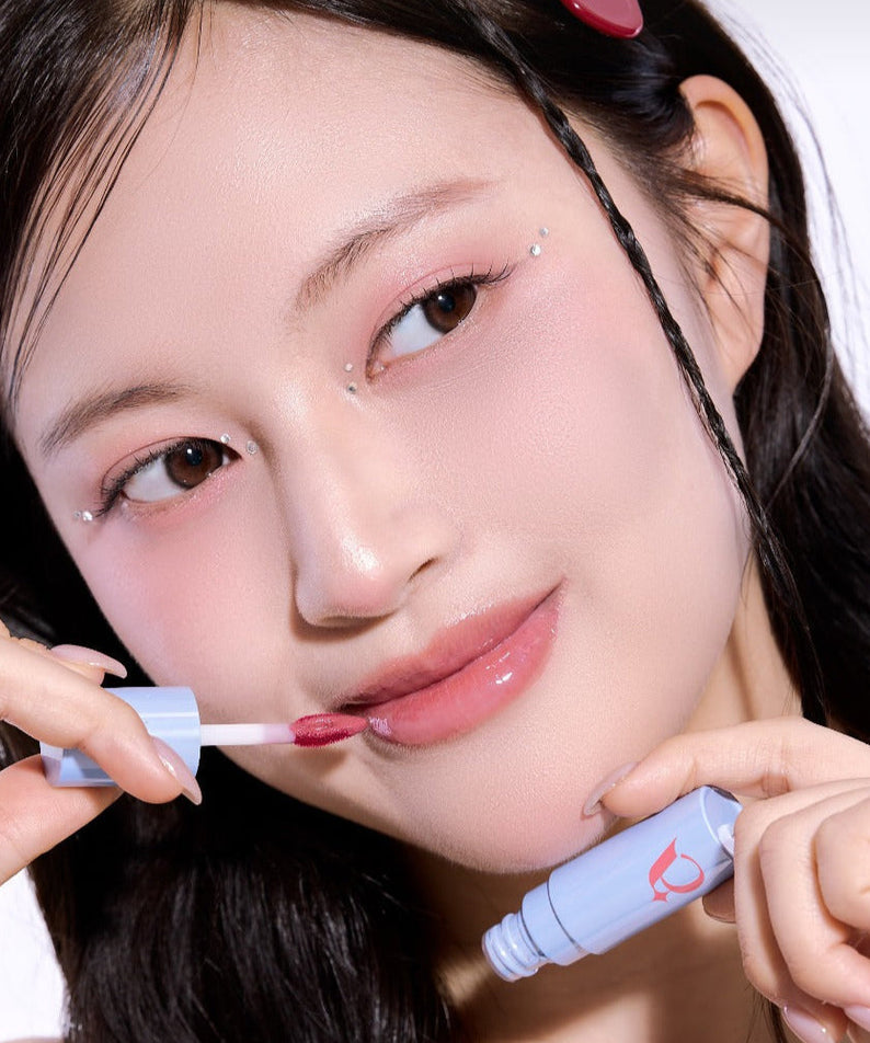 Woman applying UNLEASHIA Tanghulu Glaze Tint on lips for a glossy finish.
