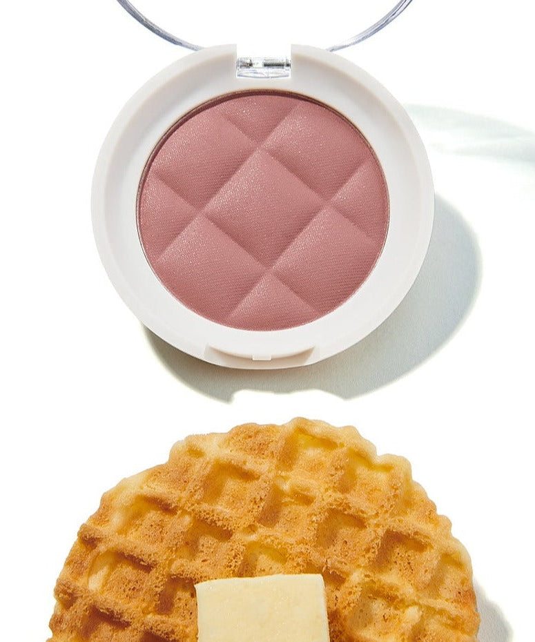 UNLEASHIA Waffle Dough Blusher in pink open compact next to a waffle on a white background