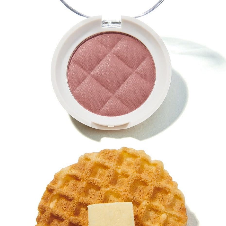 UNLEASHIA Waffle Dough Blusher in pink open compact next to a waffle on a white background