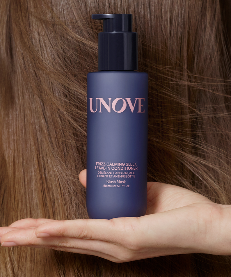 UNOVE Frizz Calming Sleek Leave-In Conditioner 150ml bottle held in hand against hair backdrop
