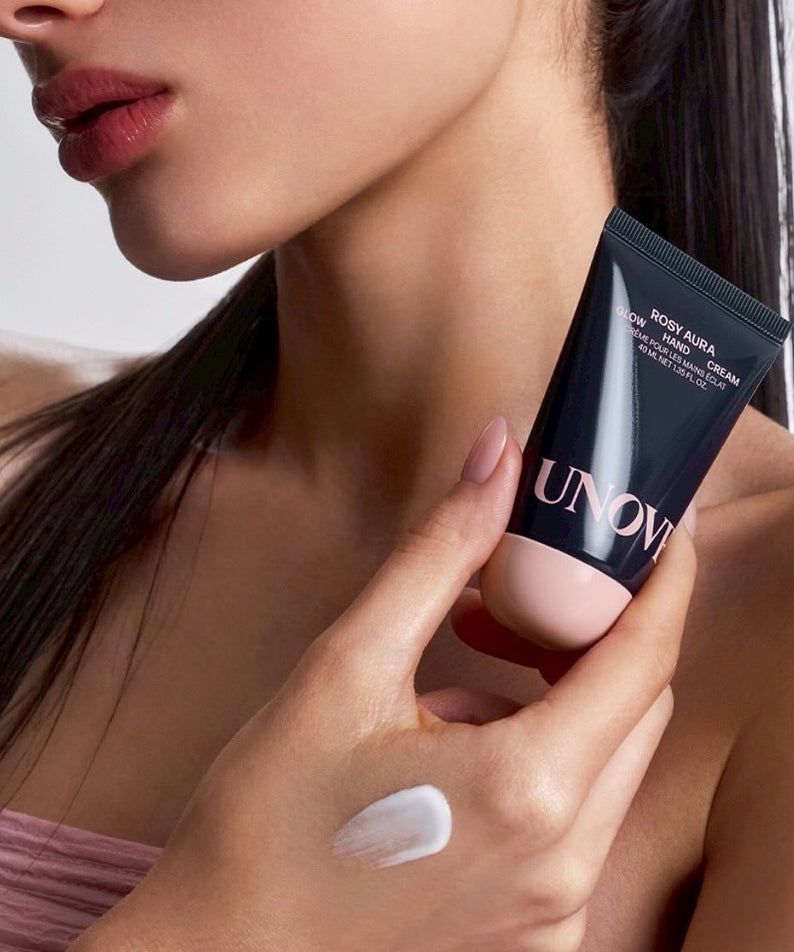 Woman holding UNOVE Glow Hand Cream 40ml, showcasing its texture on her hand.