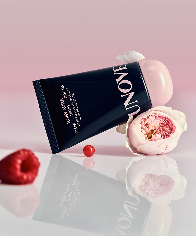 UNOVE Glow Hand Cream 40ml in pink packaging with rose and raspberry accents on a reflective surface.