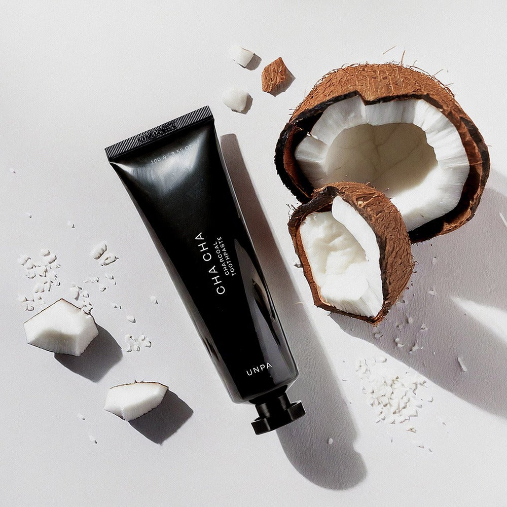 UNPA Cha Cha Charcoal Original Toothpaste 100g with coconut pieces on a white background.