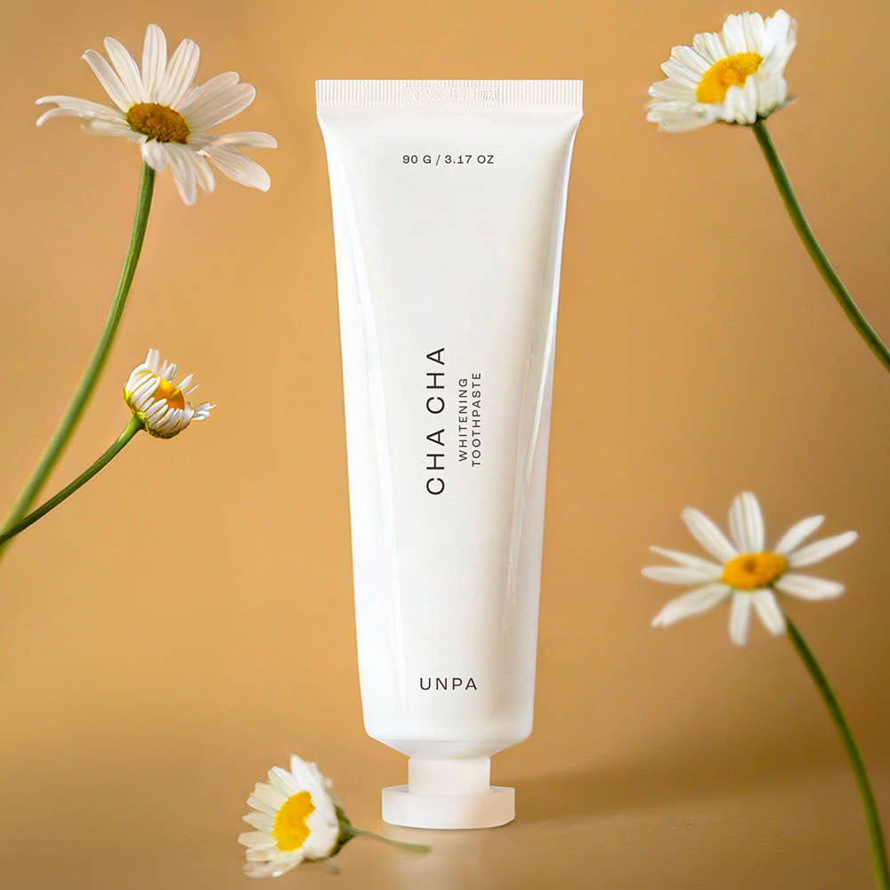 UNPA Chacha French Chamomile Vegan Whitening Toothpaste 90g with chamomile flowers on a beige background