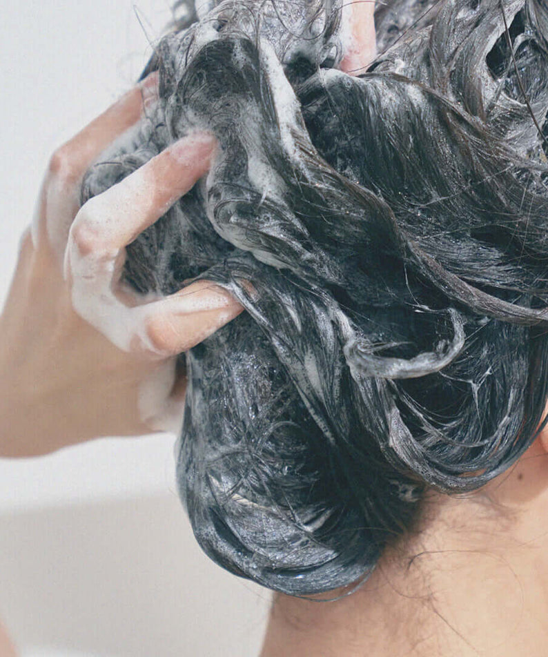 Person using URANG Moringa Scalp Strengthening Shampoo Bar, lathering and cleansing hair for healthy scalp and strong hair.