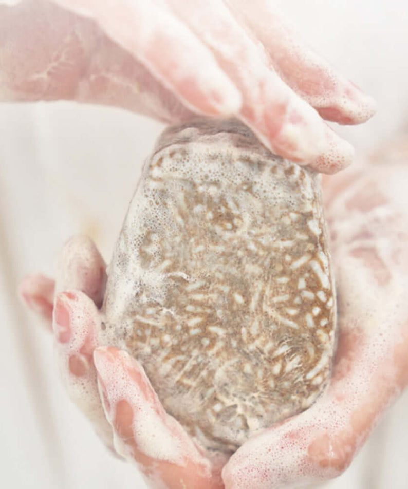 Person holding foamy URANG Mugwort Calming Shampoo Bar in hands, showcasing natural texture and soothing properties.