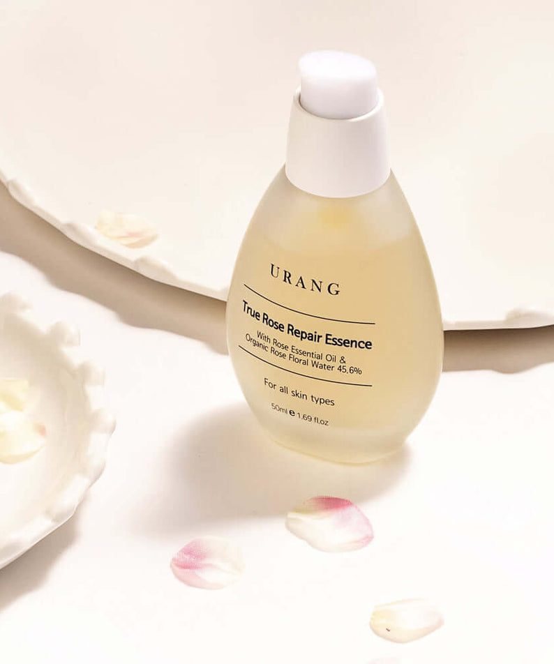 URANG True Rose Repair Essence bottle on white background with rose petals
