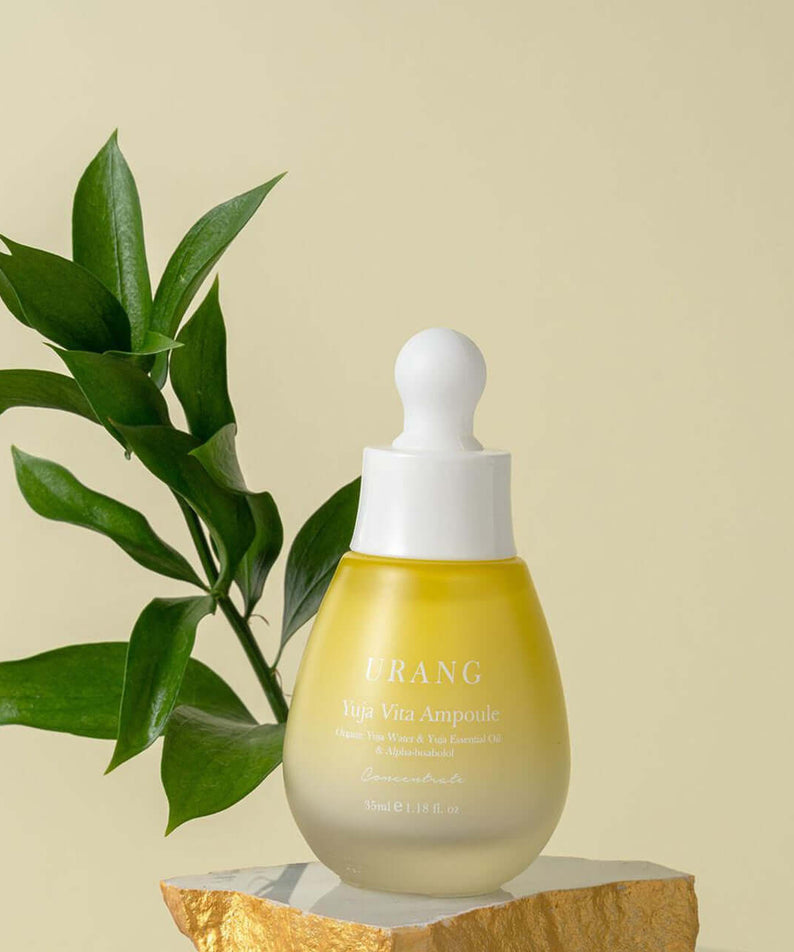 URANG Yuja Vita Ampoule bottle on a stone stand with plant background