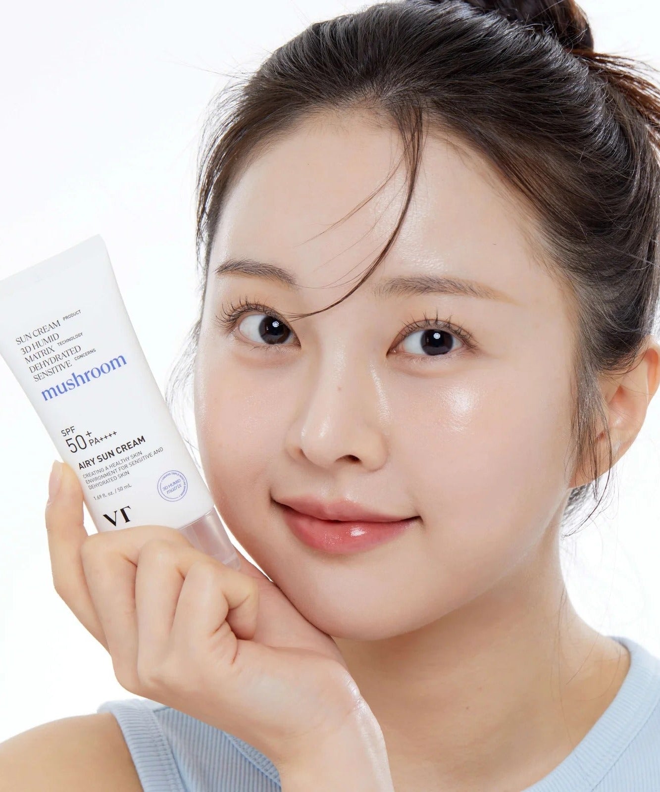 Smiling person holding VT COSMETIC Airy Sunscreen 50ml product tube close-up.