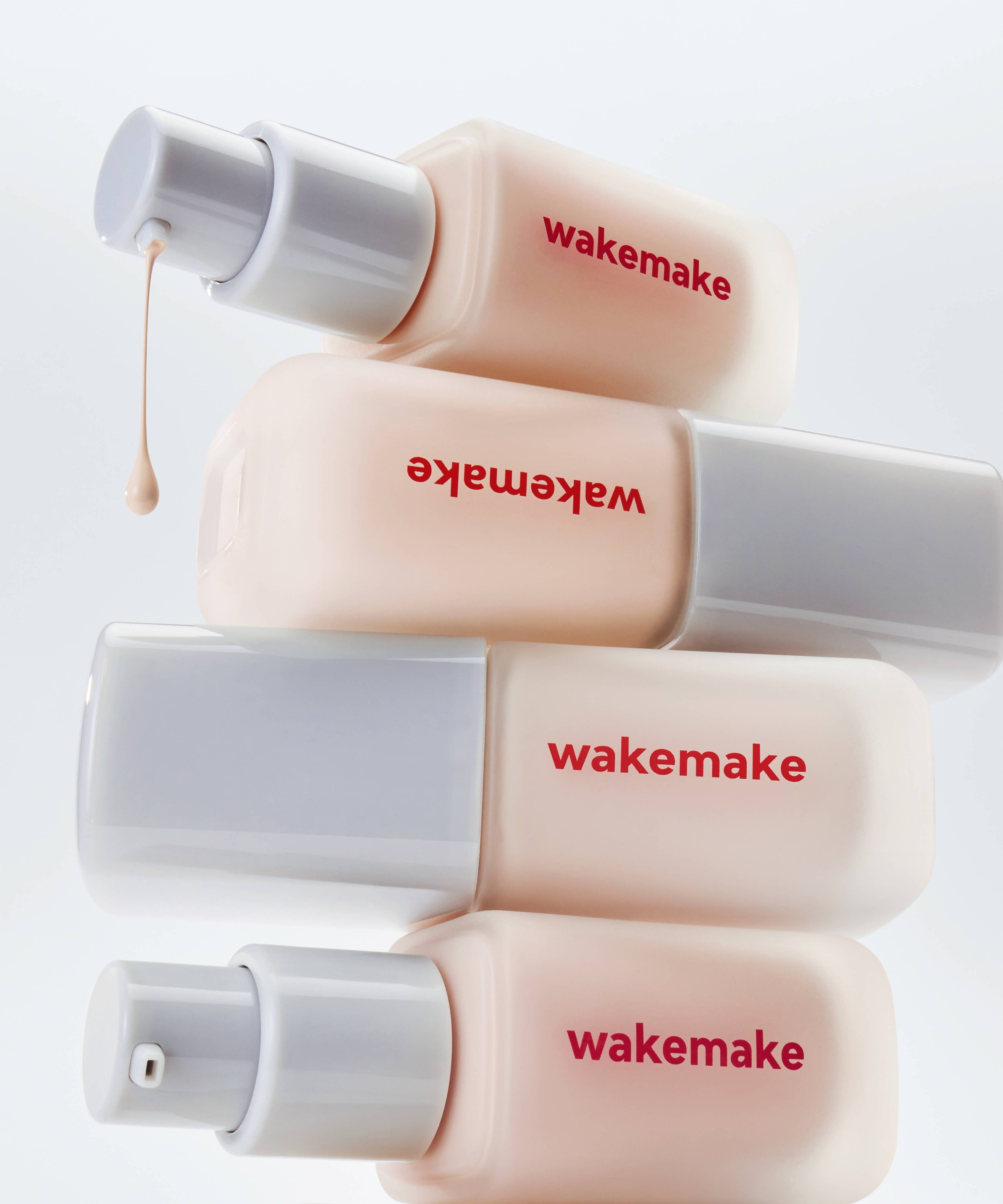 WAKE MAKE Seamless Wear Foundation 30ml bottles displayed creatively with dripping product, highlighting smooth application and finish.