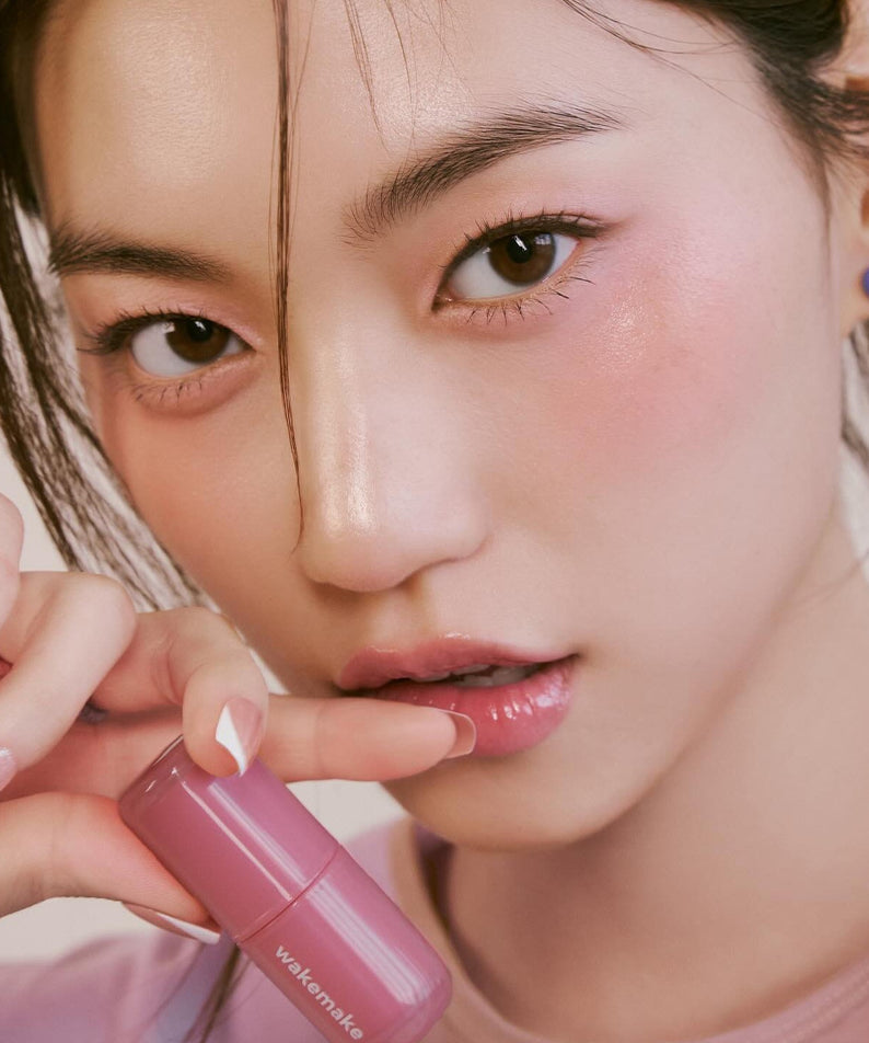 Model wearing pink shade of WAKE MAKE Waterfull Glow Tint 4.6g, showcasing vibrant and glossy lip color.