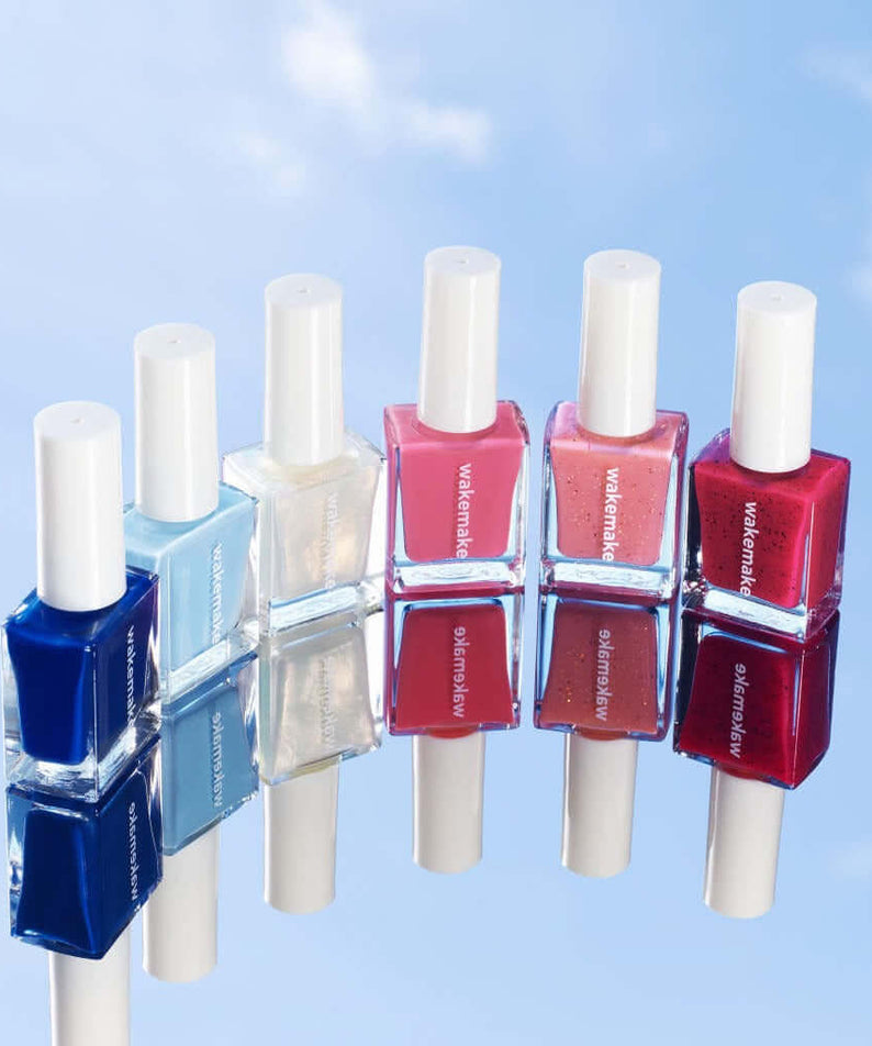 Selection of WAKEMAKE Nail Gun (#08 to #167) polishes displaying vibrant colors on a reflective surface against a sky background.