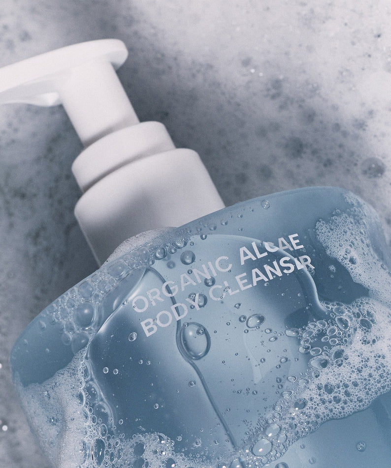 WHAMISA Organic Algae Fermented Body Cleanser 490ml surrounded by bubbles, featuring a pump dispenser against a frothy background.