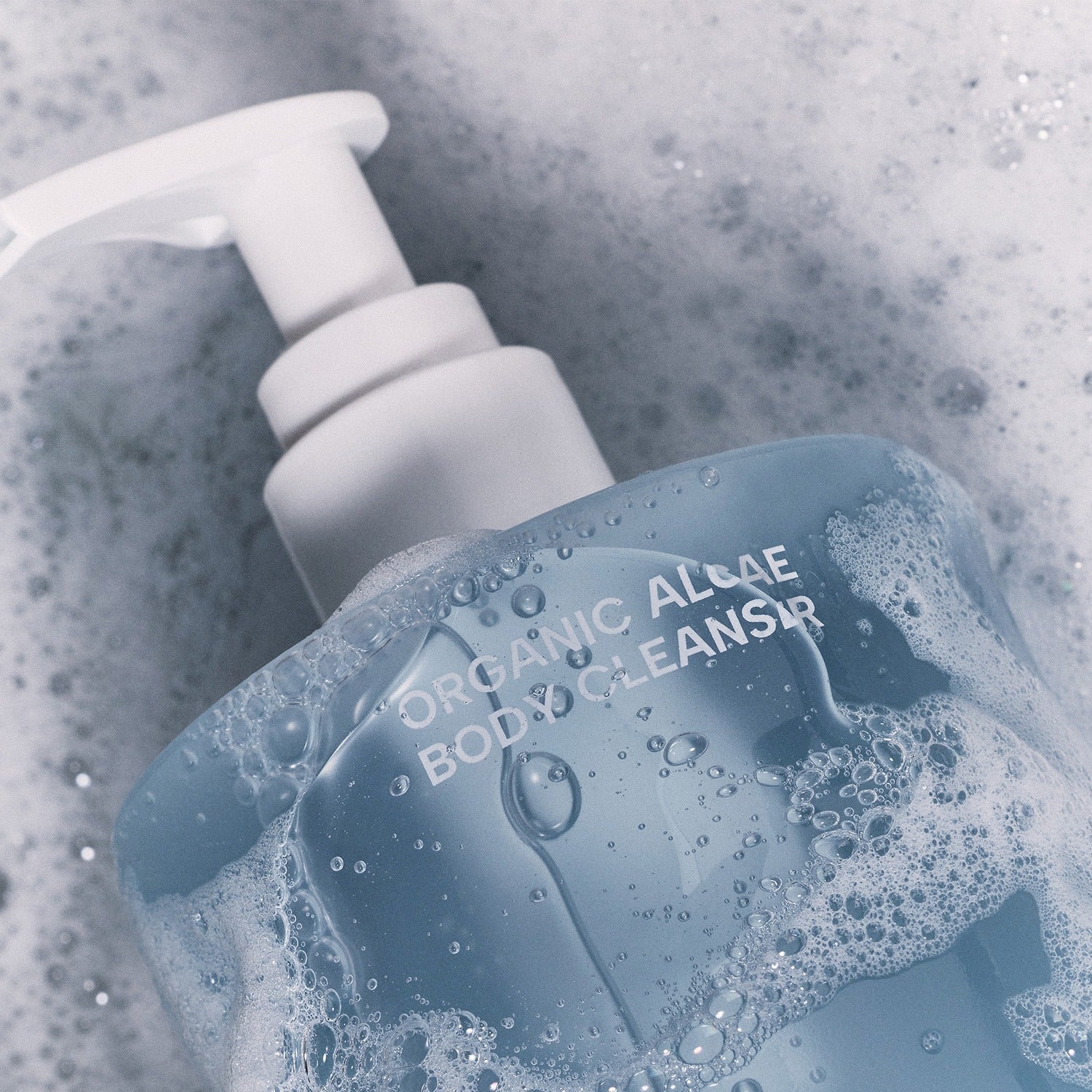 WHAMISA Organic Algae Fermented Body Cleanser 490ml surrounded by bubbles, featuring a pump dispenser against a frothy background.