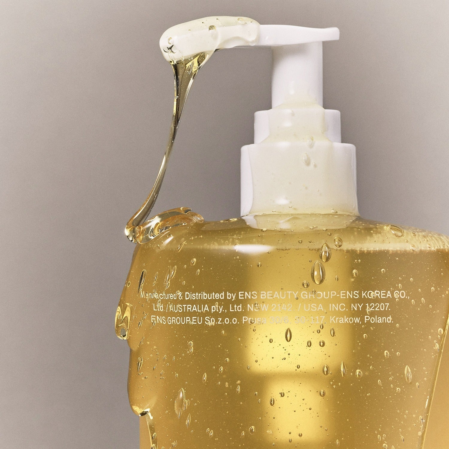Close-up of WHAMISA Organic Seed Fermented Body Cleanser 490ml bottle with pump dispenser, showing golden liquid texture and design.
