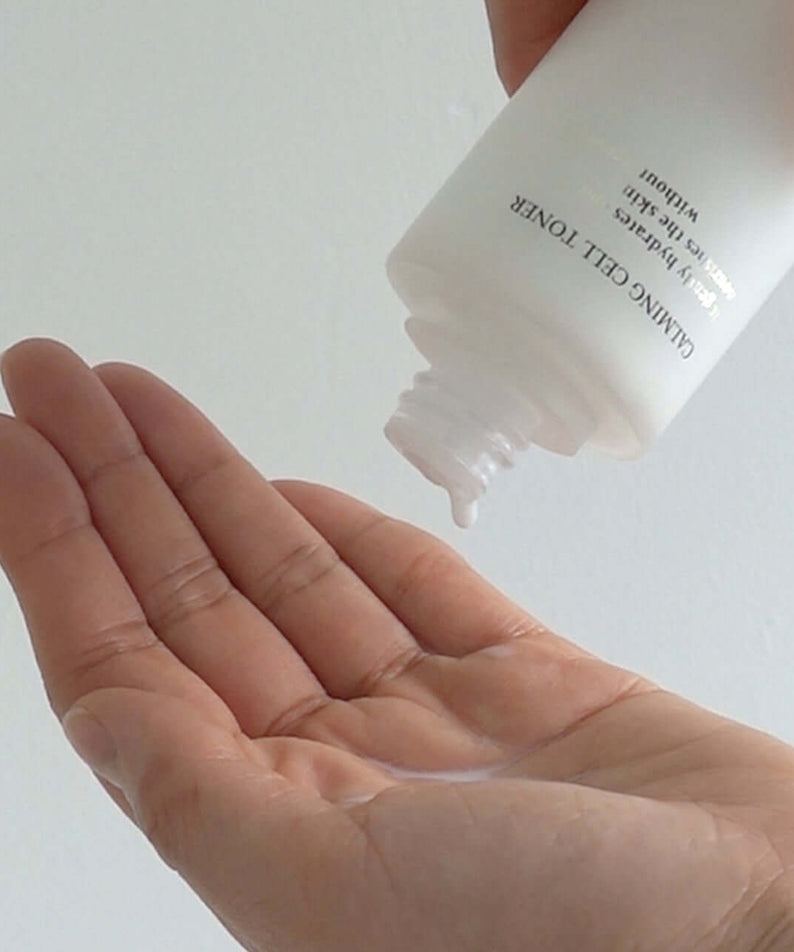 Person pouring XOUL Calming Cell Toner 130ml into their hand, showcasing the product's application.